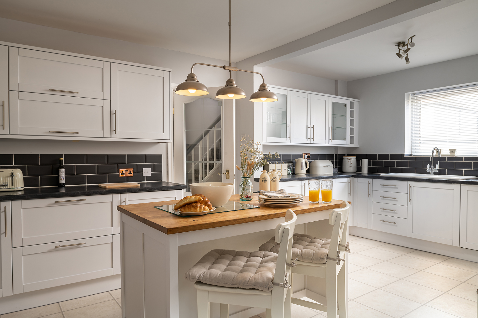 Bright white kitchen at Stuart House with a wooden breakfast island
