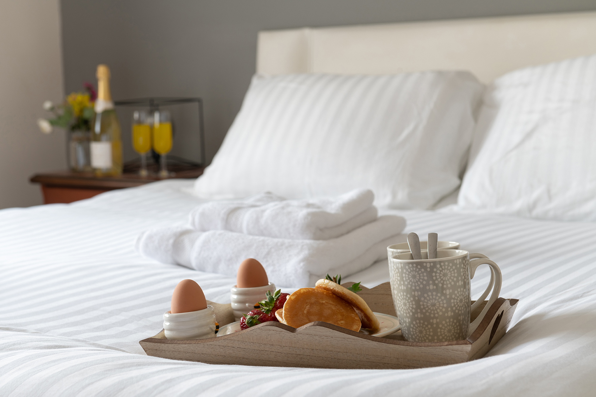 Fresh white bed linen with towels and a breakfast tray